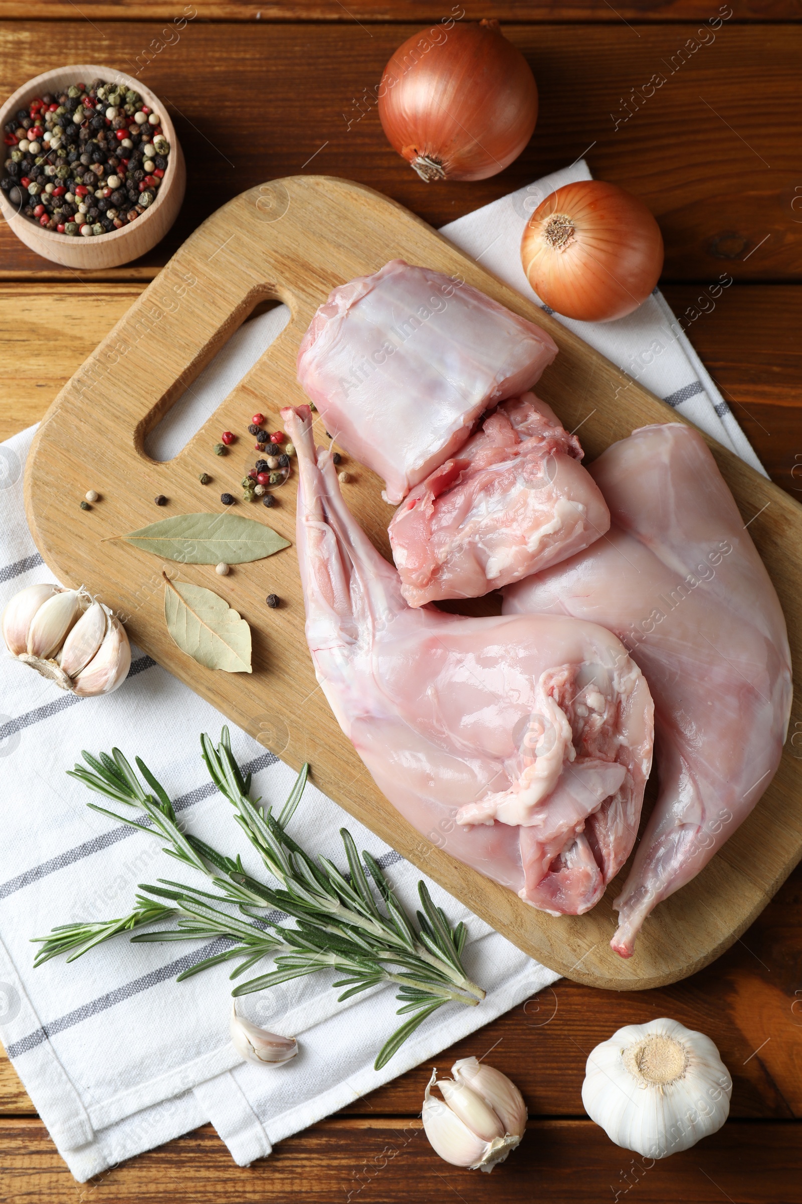 Photo of Fresh raw rabbit meat and spices on wooden table, flat lay