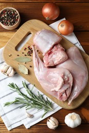 Photo of Fresh raw rabbit meat and spices on wooden table, flat lay