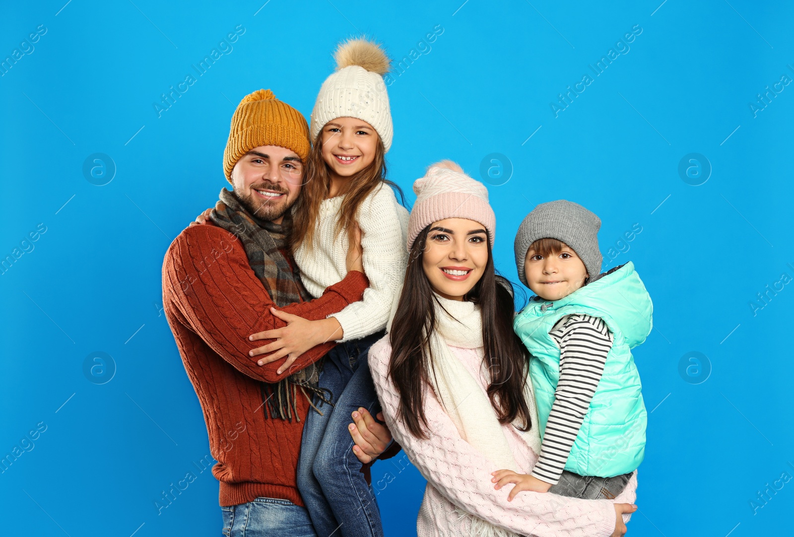 Photo of Happy family in warm clothes on blue background. Winter vacation