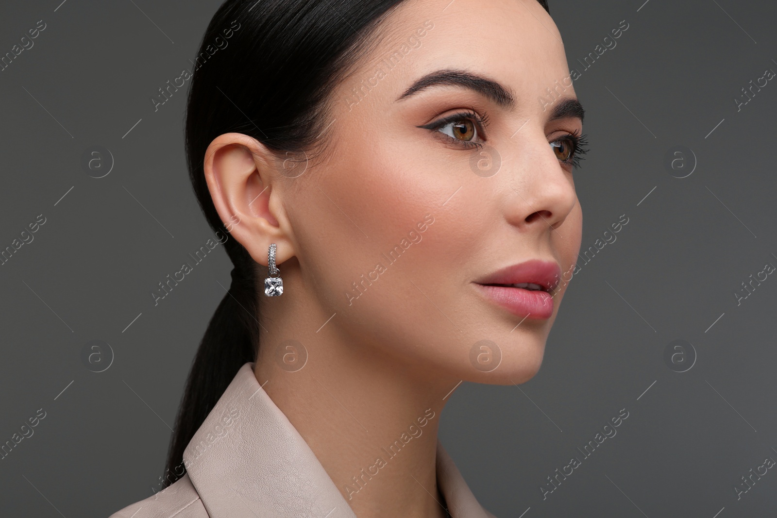 Photo of Beautiful young woman with elegant earrings on dark grey background, closeup