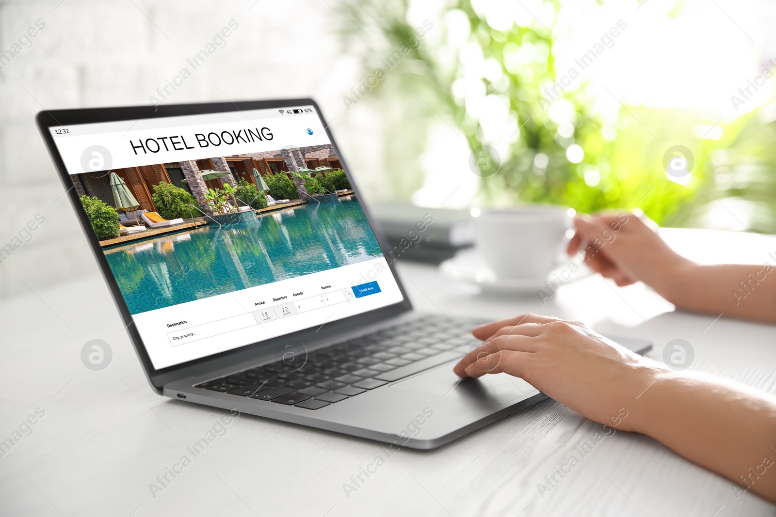 Image of Woman using laptop to book hotel at white wooden table, closeup