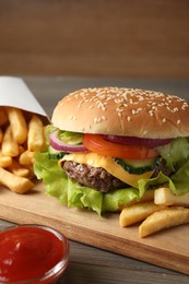 Delicious burger, ketchup and french fries served on wooden table, closeup