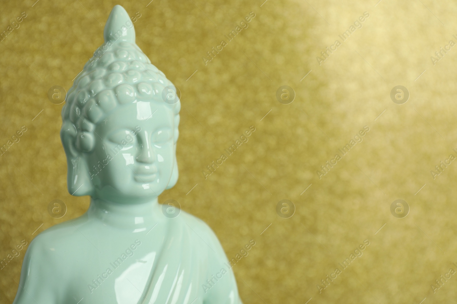 Photo of Buddha statue on golden background, closeup. Space for text