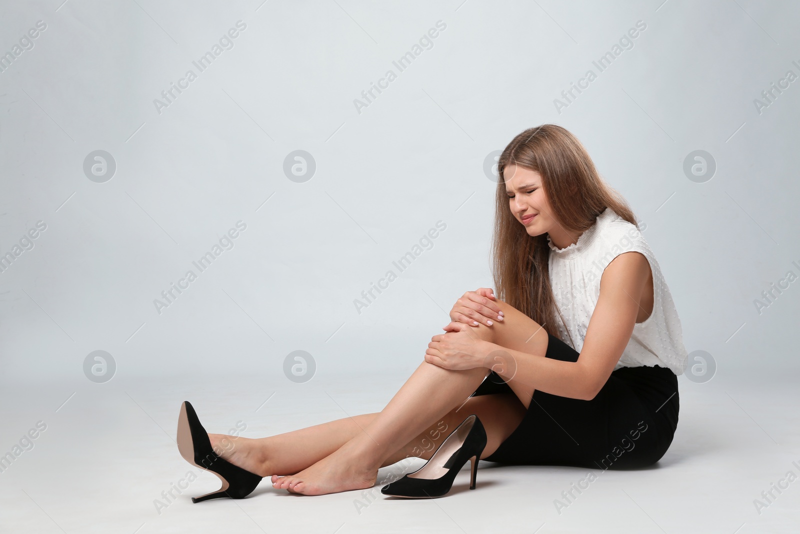 Photo of Full length portrait of businesswoman with knee problems sitting on grey background