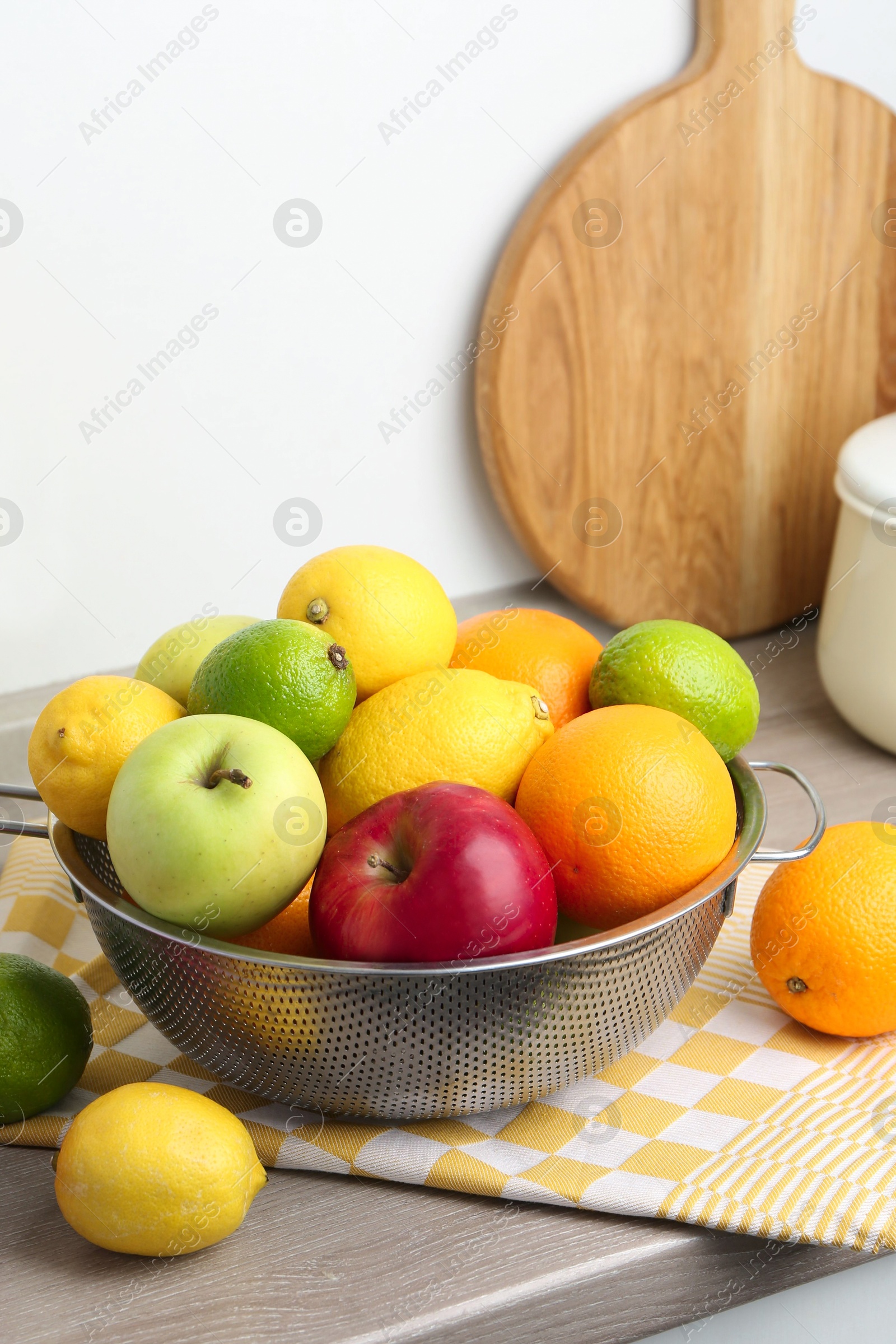 Photo of Metal colander with different fruits on countertop in kitchen