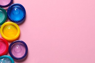 Photo of Colorful condoms on pink background, flat lay. Space for text
