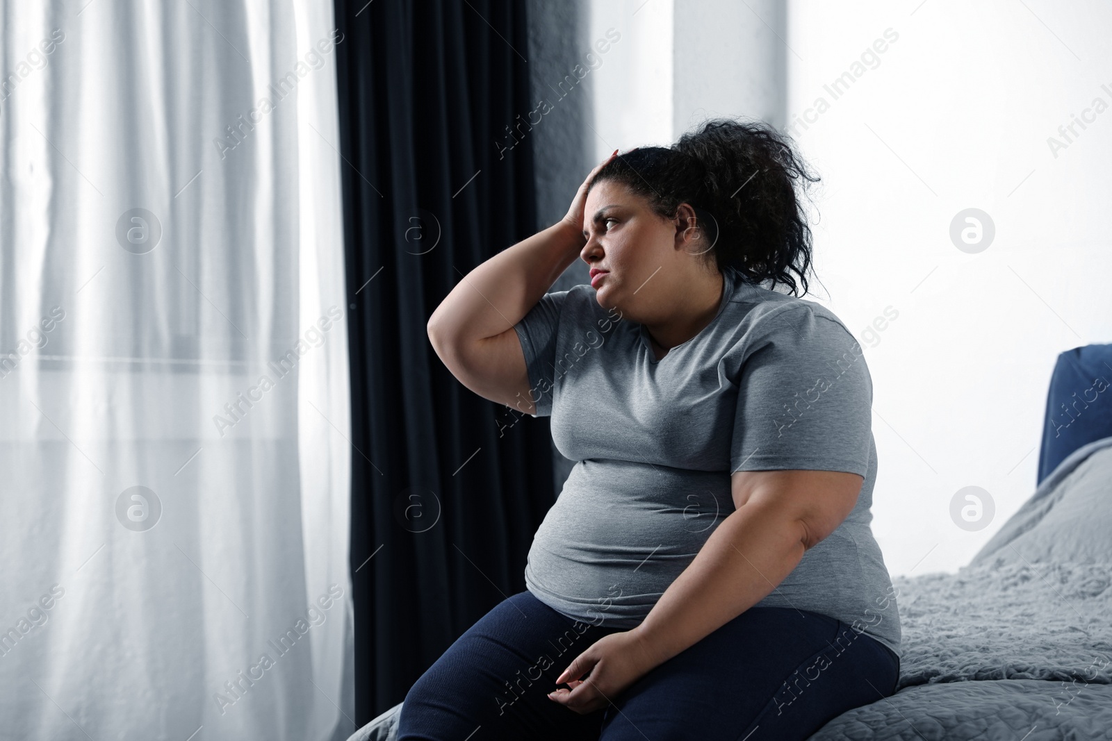 Photo of Depressed overweight woman on bed at home