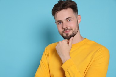 Photo of Handsome man in yellow sweatshirt on light blue background, space for text