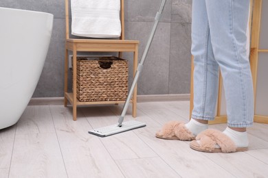 Photo of Woman cleaning parquet floor with mop in bathroom, closeup