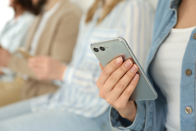 Young woman using modern smartphone indoors, closeup