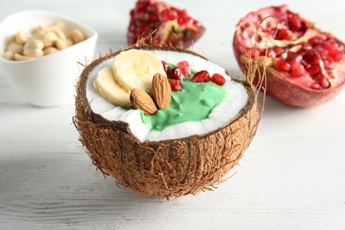 Yummy spirulina smoothie in coconut and pomegranate on wooden background, closeup