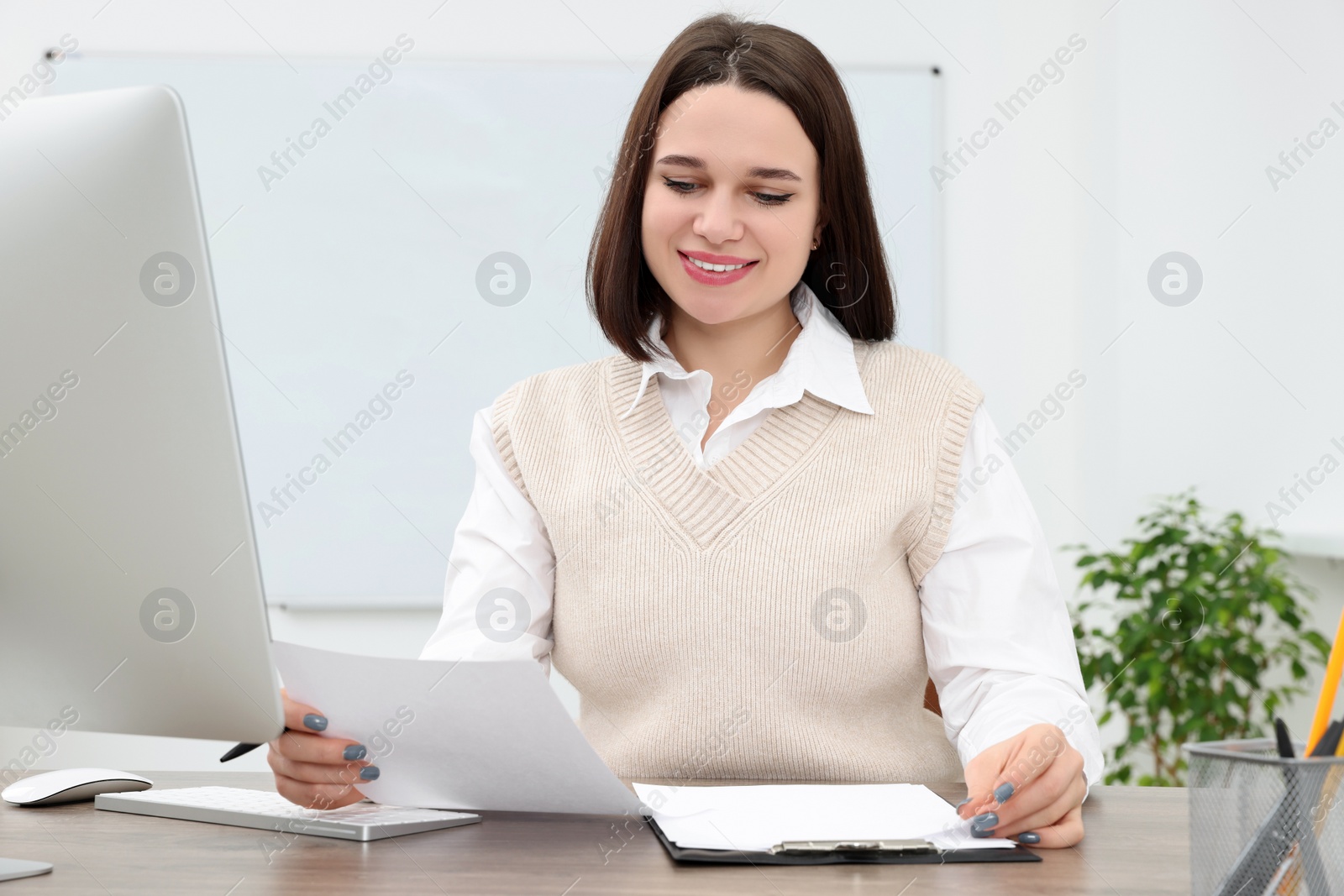 Photo of Happy young intern working at table in modern office