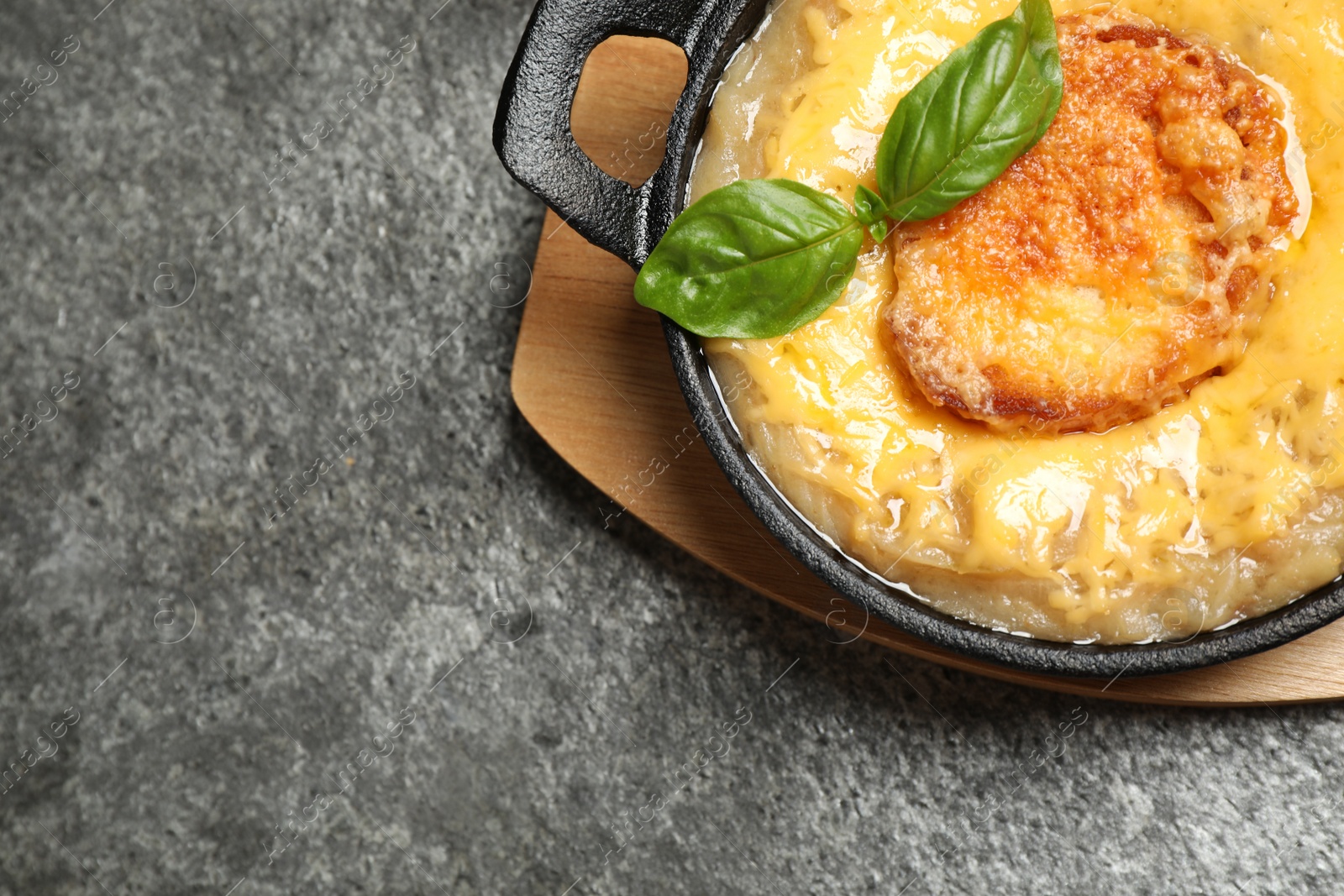 Photo of Tasty homemade french onion soup served on grey table, top view. Space for text