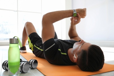 Photo of Man checking fitness tracker during training in gym