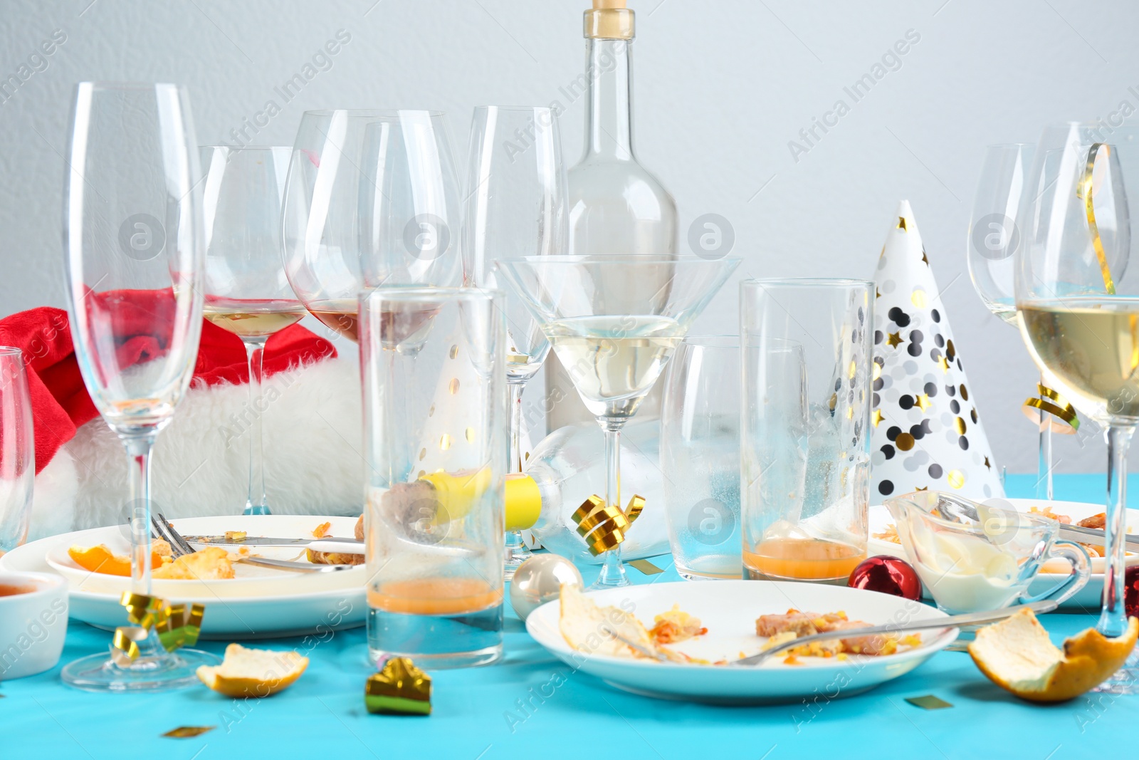 Photo of Dirty tableware with leftovers on light blue cloth after party