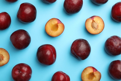 Delicious ripe plums on light blue background, flat lay