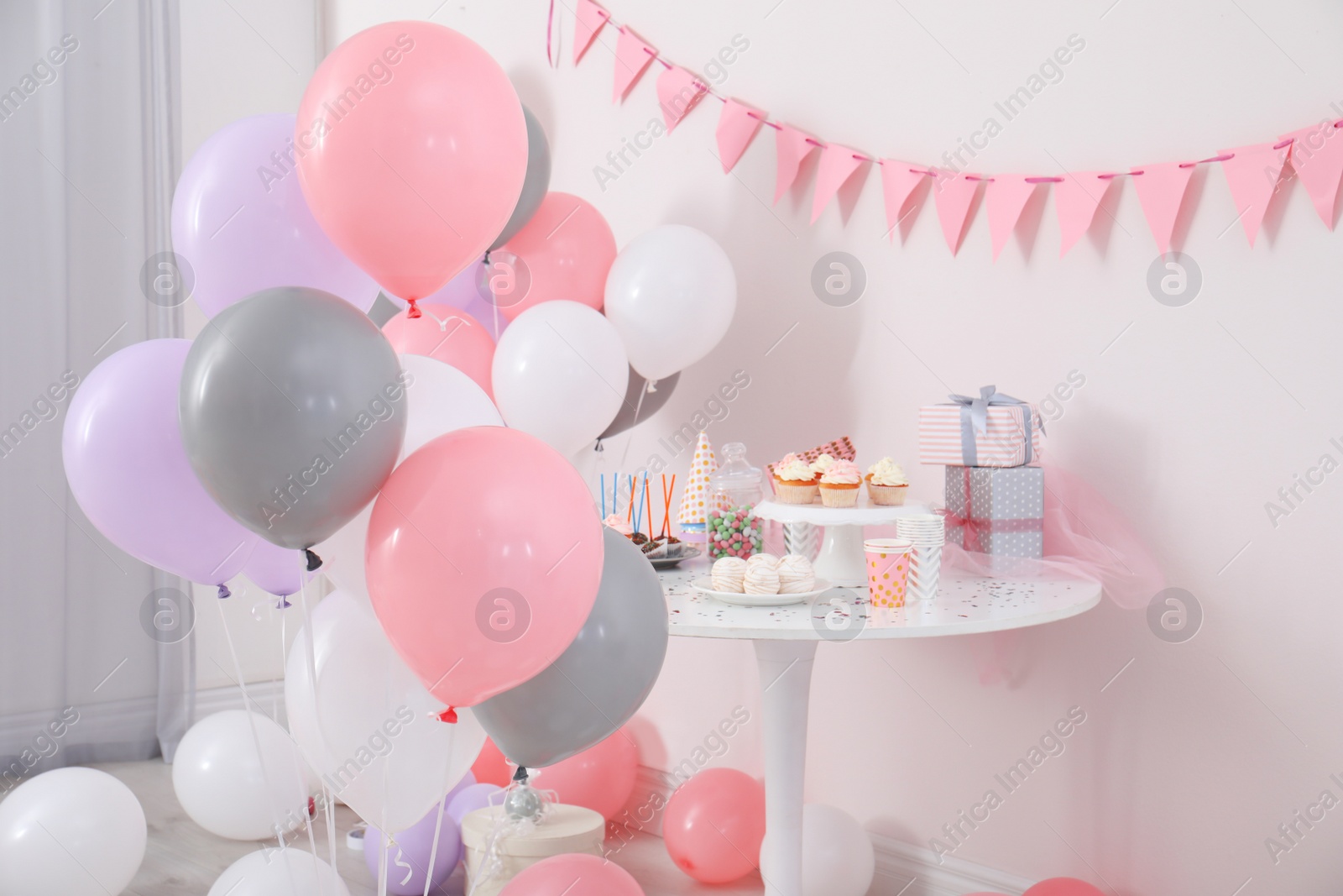 Photo of Party treats and items on table in room decorated with balloons