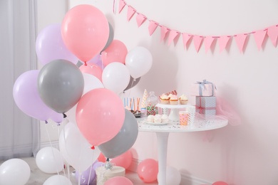 Photo of Party treats and items on table in room decorated with balloons