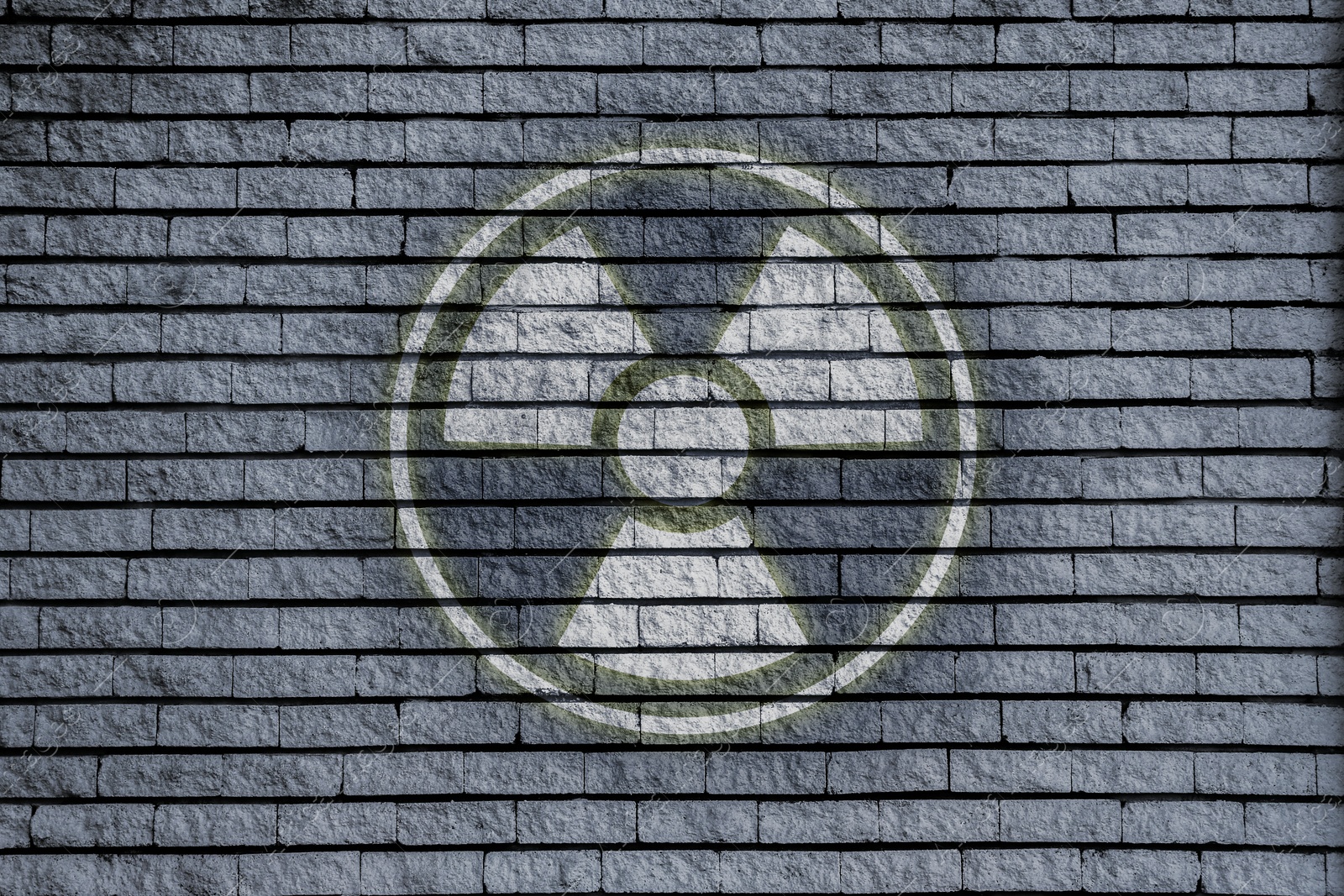 Image of Radioactive sign on grey brick wall. Hazard symbol