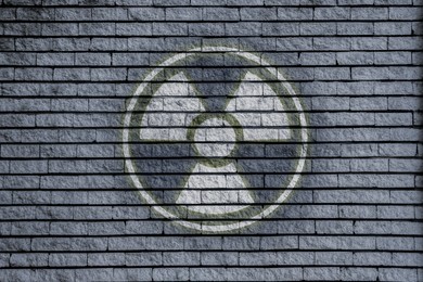 Image of Radioactive sign on grey brick wall. Hazard symbol