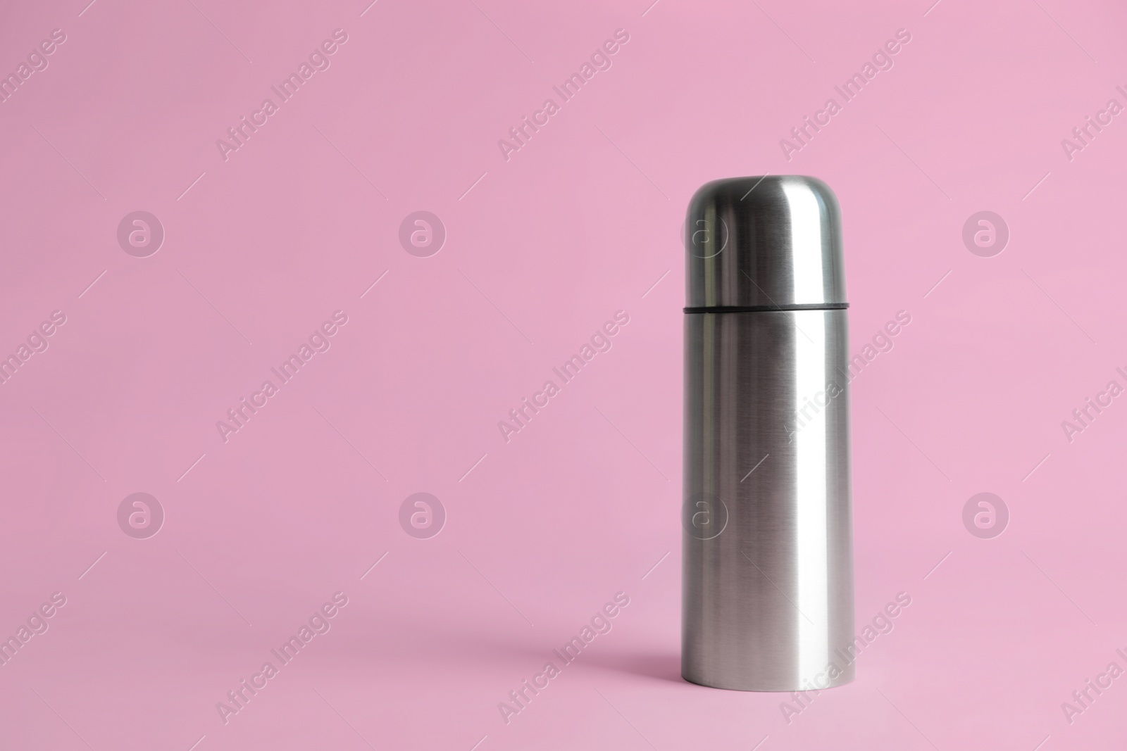 Photo of Stylish thermo bottle on pink background, space for text