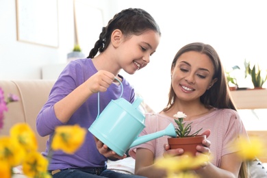 Mother and daughter watering potted plants at home