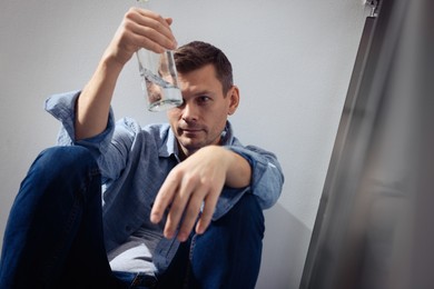 Photo of Addicted man with alcoholic drink near beige wall