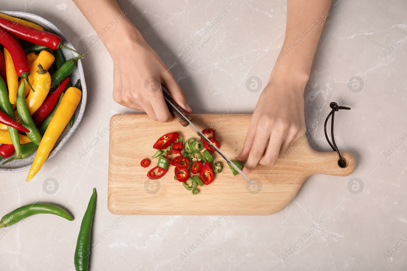 Photo of Woman cutting chili peppers at table, top view