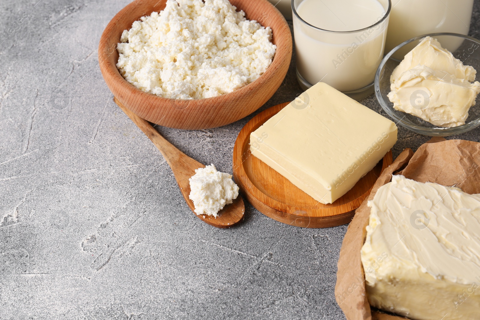 Photo of Tasty homemade butter and dairy products on grey table. Space for text