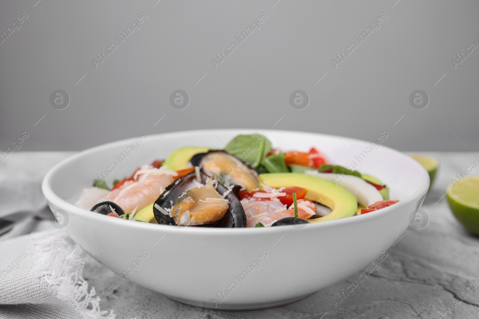Photo of Bowl of delicious salad with seafood on white textured table