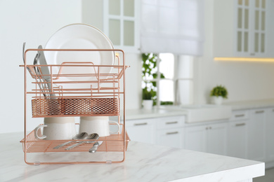 Photo of Clean dishes on drying rack in modern kitchen interior, space for text