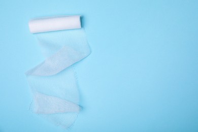 Photo of White medical bandage on light blue background, top view. Space for text