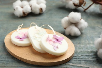 Photo of Scented sachets and cotton flowers on blue wooden table