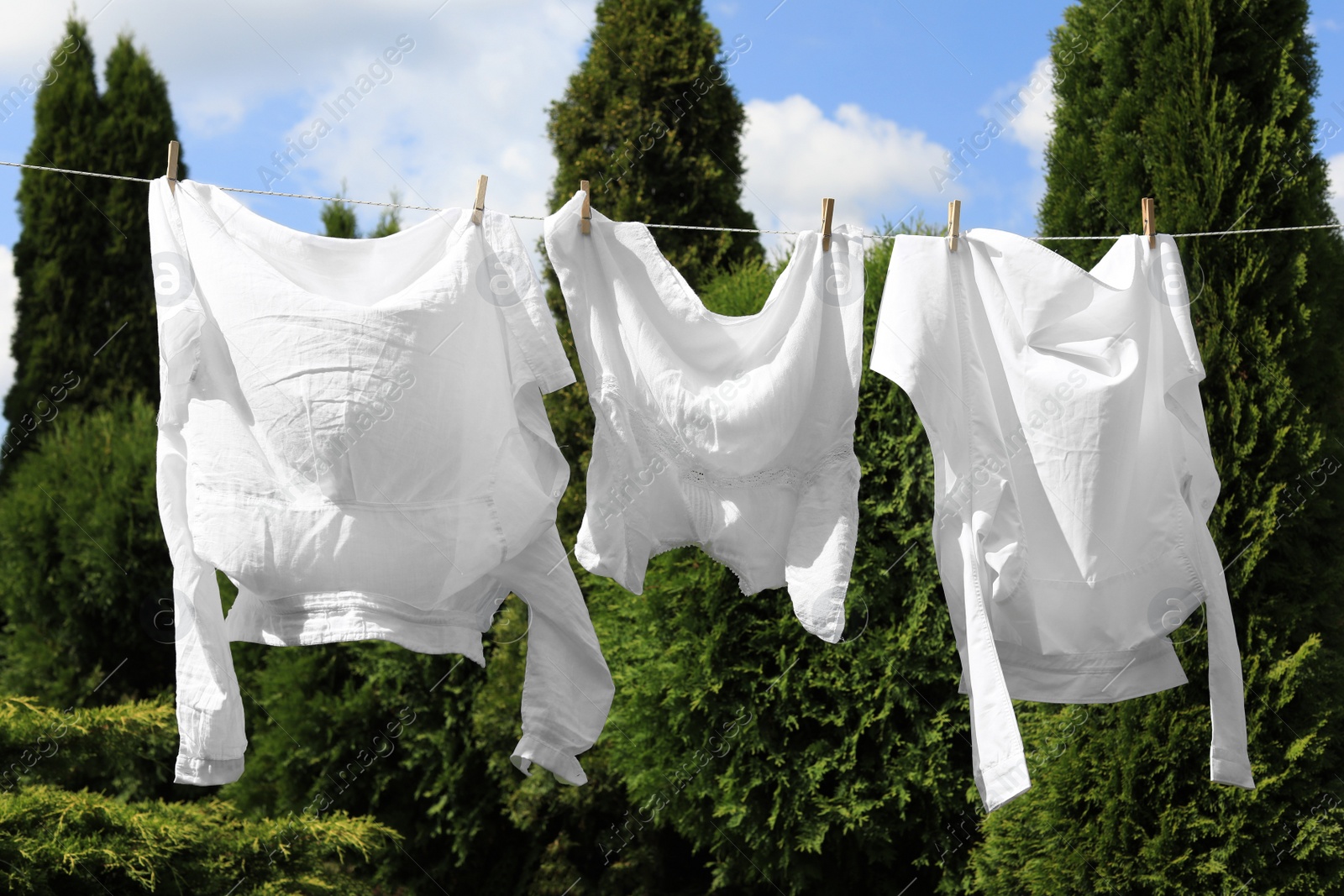 Photo of Clean clothes hanging on washing line in garden. Drying laundry