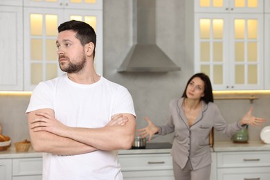 Photo of Husband trying to ignore his wife in kitchen, selective focus. Relationship problems