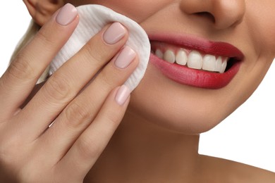 Photo of Smiling woman removing makeup with cotton pad on white background, closeup