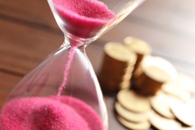Photo of Hourglass with flowing sand on table, closeup. Time management