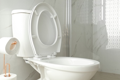 Photo of Toilet bowl near shower stall in modern bathroom interior