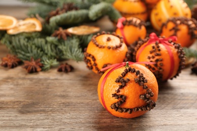Photo of Pomander balls made of fresh tangerines with cloves  on wooden table, space for text. Christmas atmosphere