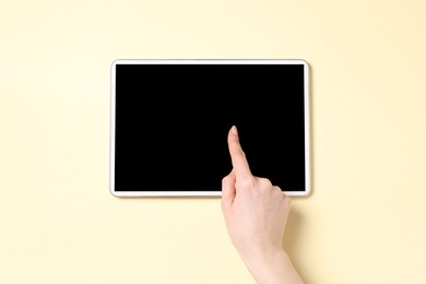 Online store. Woman using tablet on beige background, top view