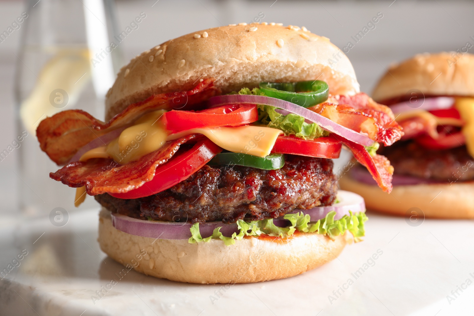 Photo of Tasty burger with bacon on table, closeup