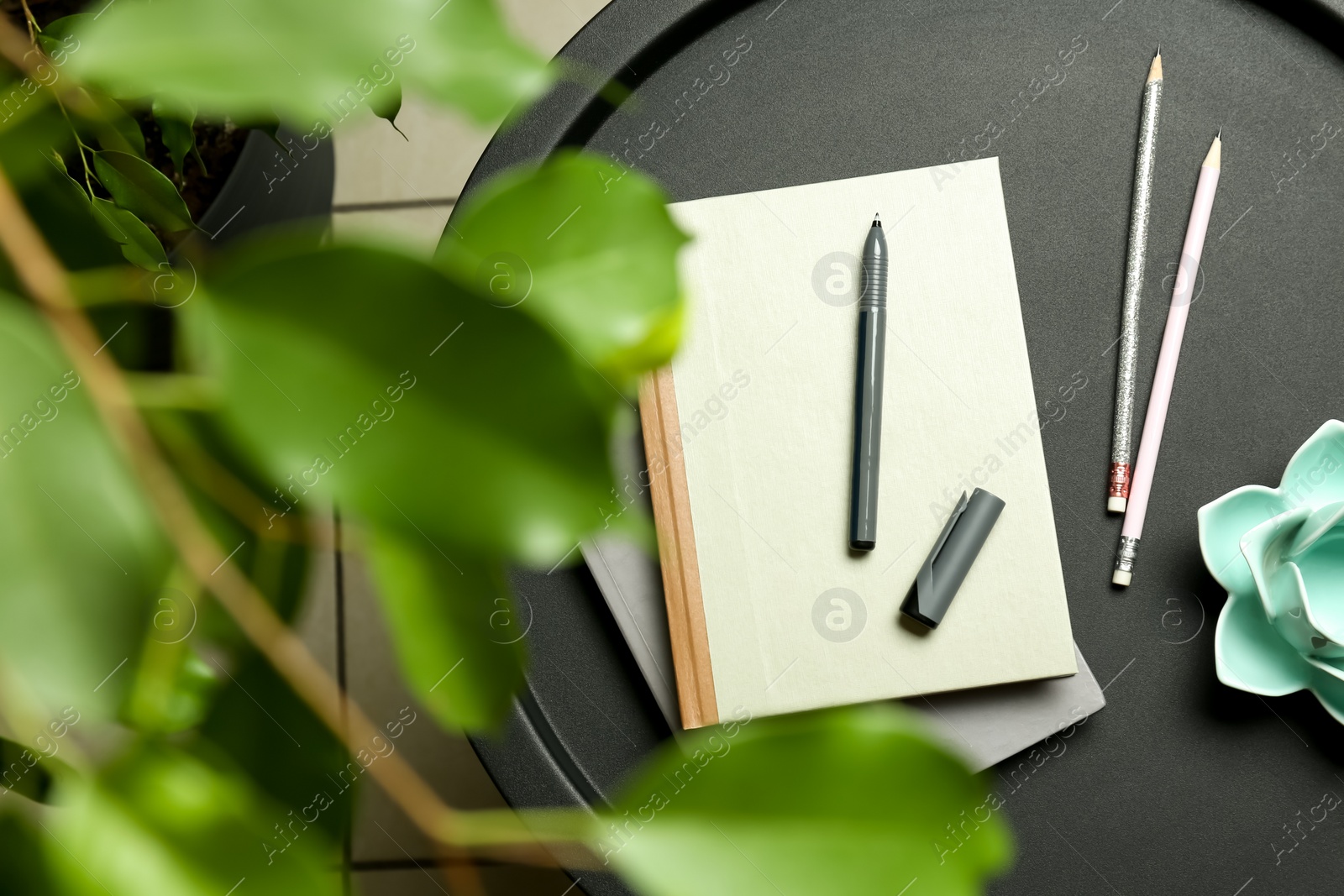 Photo of Notebooks, pen, pencils and decor on round table indoors, top view
