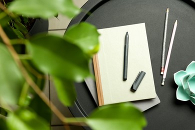 Notebooks, pen, pencils and decor on round table indoors, top view