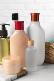 Photo of Shampoo bottles, hair mask, essential oil and towels on white marble table