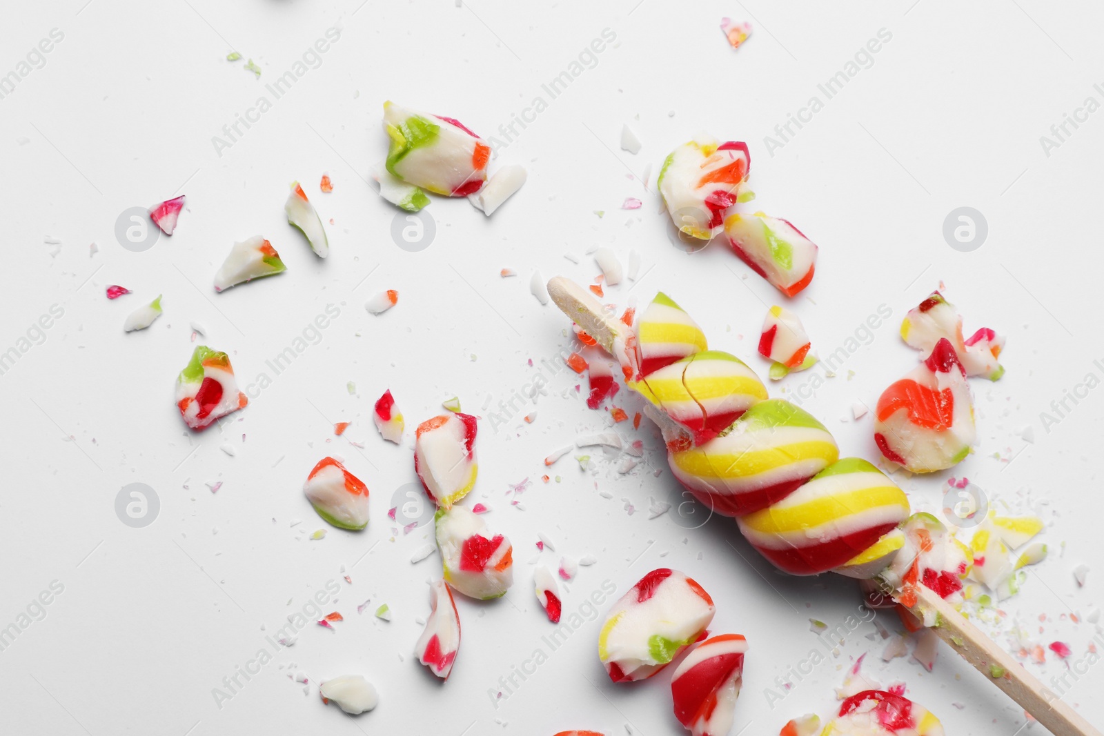 Photo of Smashed sweet lollipop on light background, top view