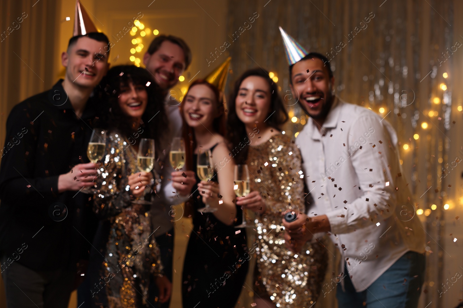 Photo of Blurred view of happy friends with glasses of sparkling wine celebrating birthday indoors