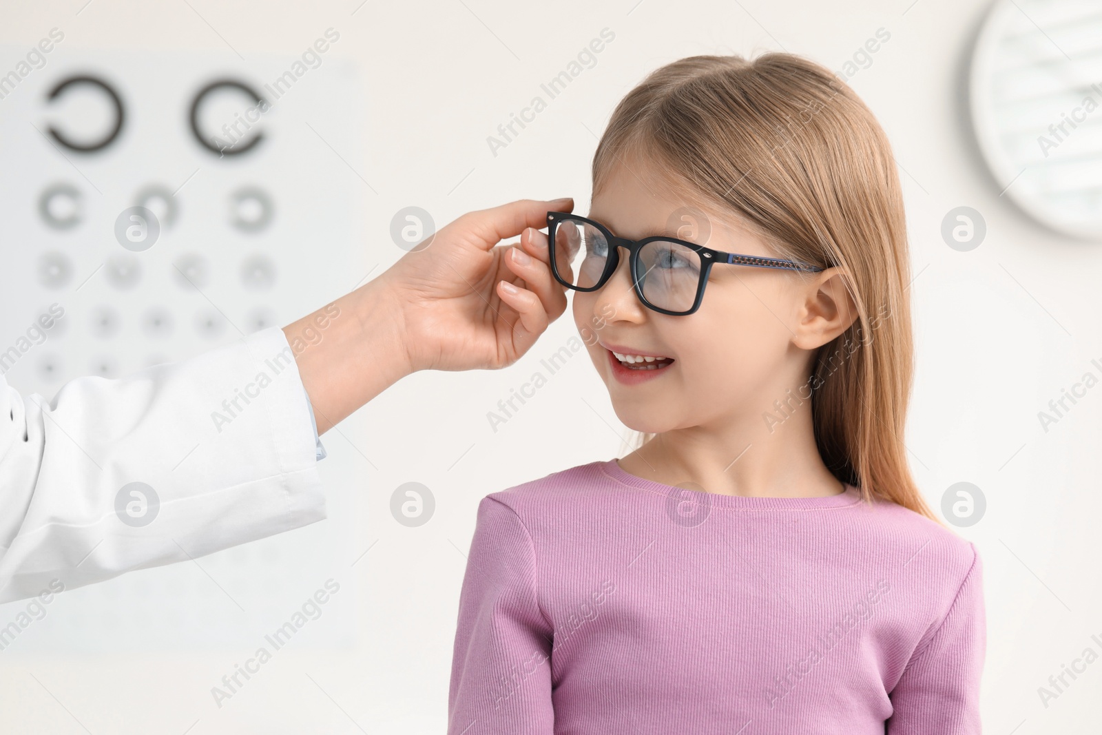 Photo of Vision testing. Little girl trying glasses at ophthalmologist office