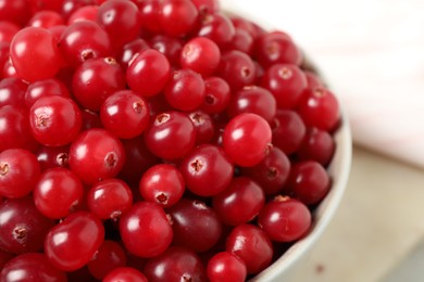 Bowl with tasty ripe cranberries on table, closeup