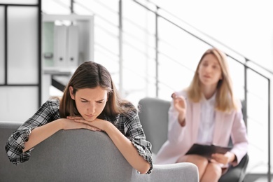 Photo of Child psychologist working with teenage girl in office
