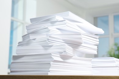 Photo of Stacks of paper sheets on wooden table indoors, closeup